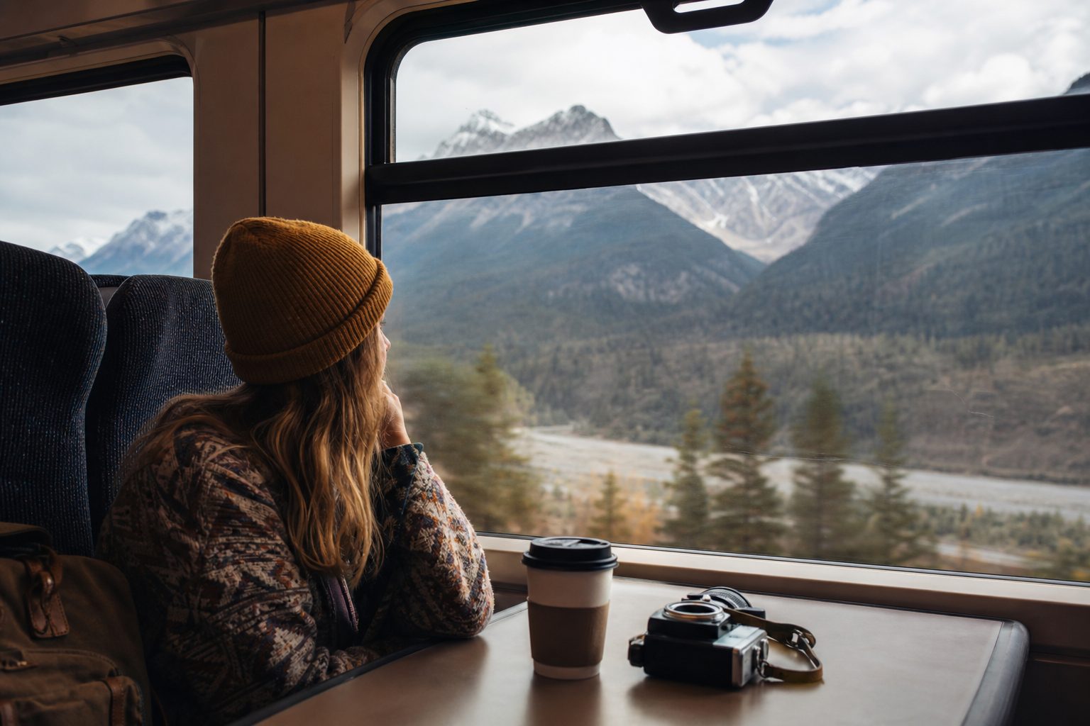 Solo traveler looking out a train window at mountains
